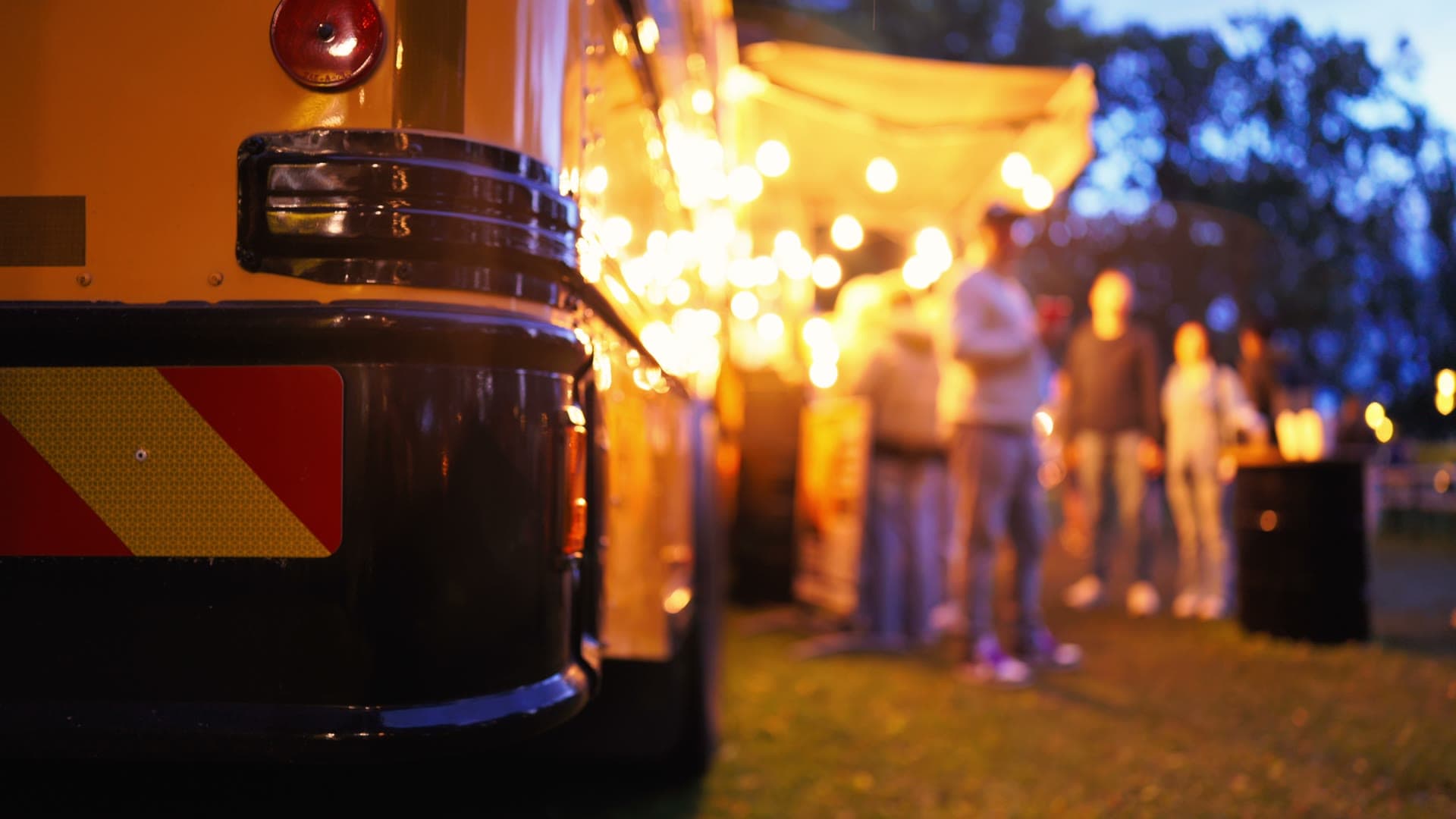 Food truck illuminé au crépuscule, avec des visiteurs réunis à proximité