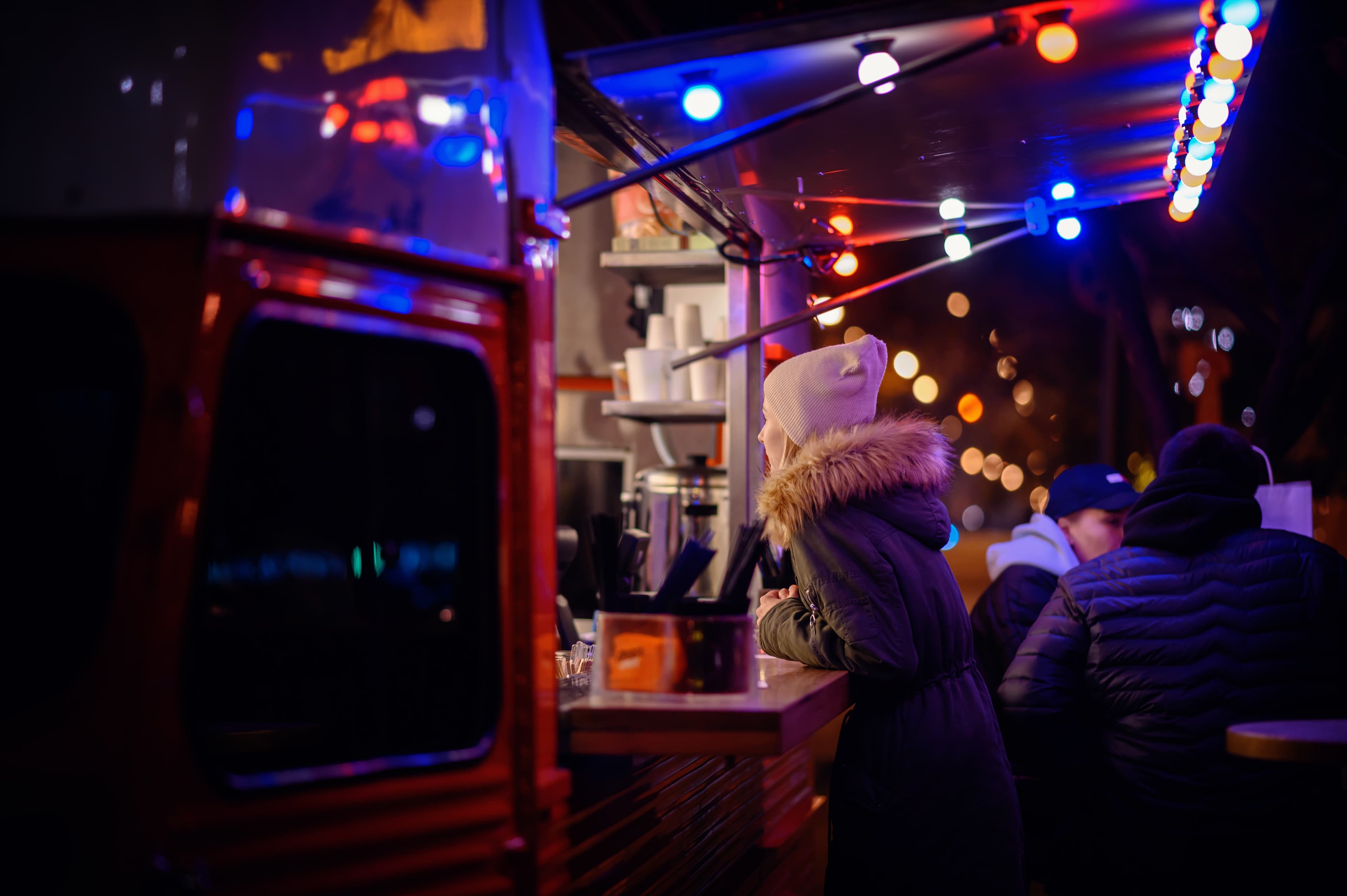 Visiteurs attendant au comptoir d’un food truck lors d’un événement nocturne